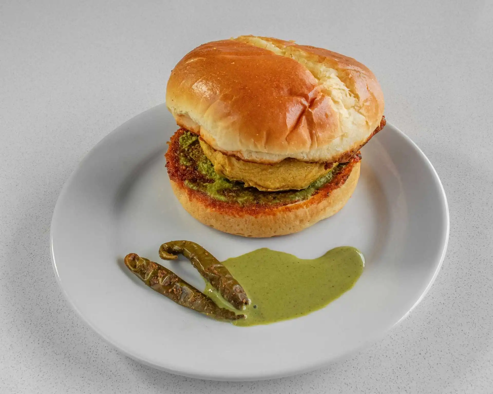 Crispy fried patty in a soft bun with green chutney at Dak Land Restaurant in Warman